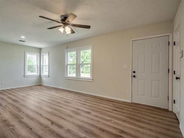 empty room featuring a ceiling fan, baseboards, visible vents, and wood finished floors