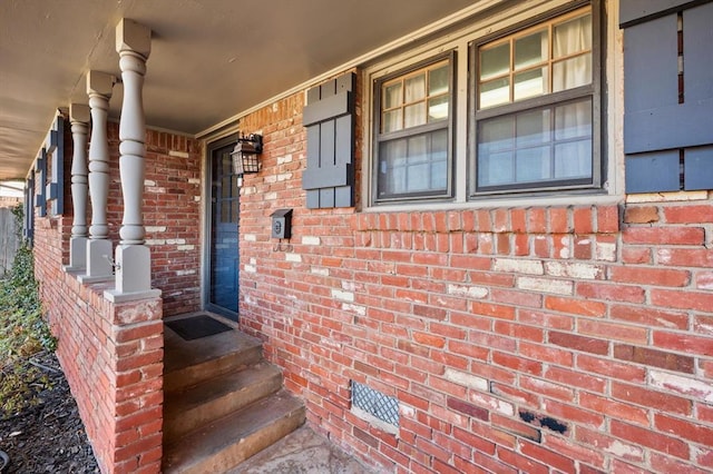 entrance to property featuring brick siding and a porch