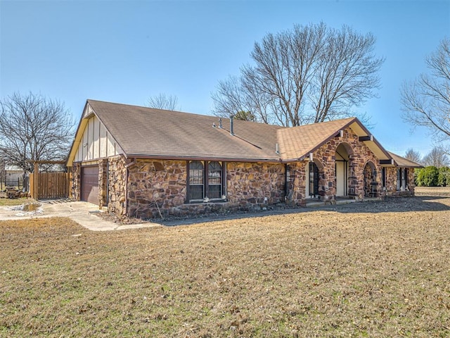 view of front facade with a front lawn, a garage, fence, and stone siding