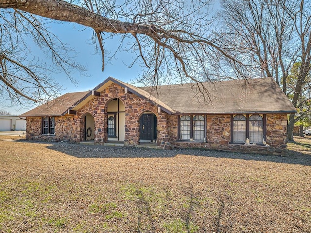 view of front of property featuring a front lawn and stone siding