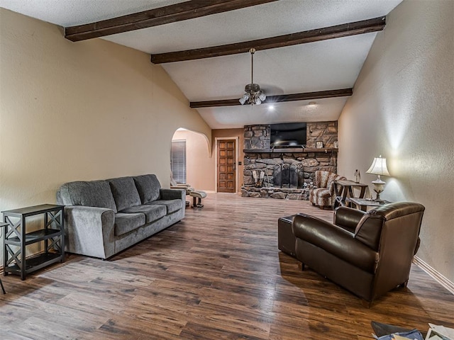 living room featuring a stone fireplace, lofted ceiling with beams, wood finished floors, and arched walkways