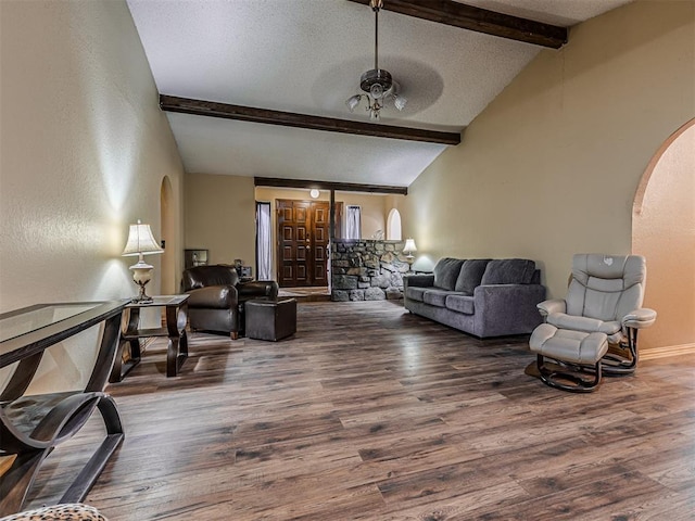 living room featuring arched walkways, a textured ceiling, lofted ceiling with beams, and wood finished floors