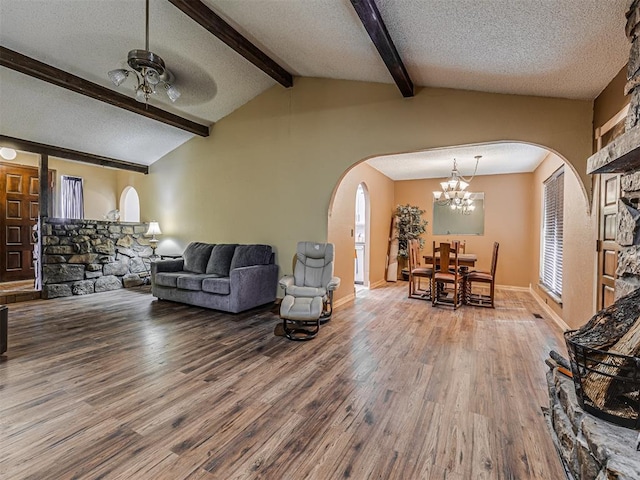 living area with vaulted ceiling with beams, a textured ceiling, ceiling fan, and wood finished floors