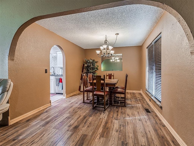 dining area with visible vents, a textured ceiling, wood finished floors, and a textured wall