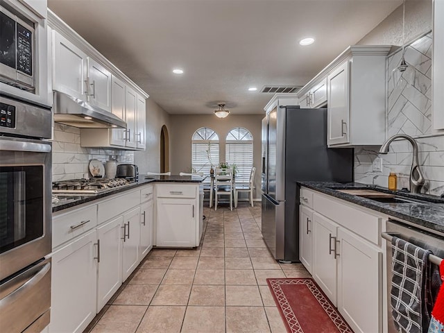 kitchen featuring a warming drawer, a sink, under cabinet range hood, stainless steel appliances, and white cabinets