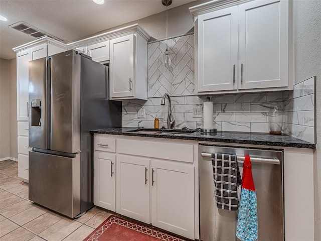 kitchen featuring a sink, tasteful backsplash, white cabinetry, stainless steel appliances, and light tile patterned floors