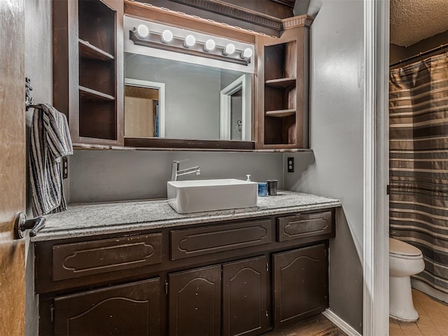 bathroom featuring vanity, toilet, baseboards, and a textured ceiling