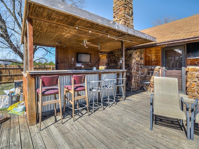 wooden deck with a ceiling fan, fence, and outdoor dry bar