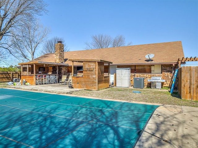 back of house with outdoor dry bar, fence, central AC unit, a chimney, and a patio area