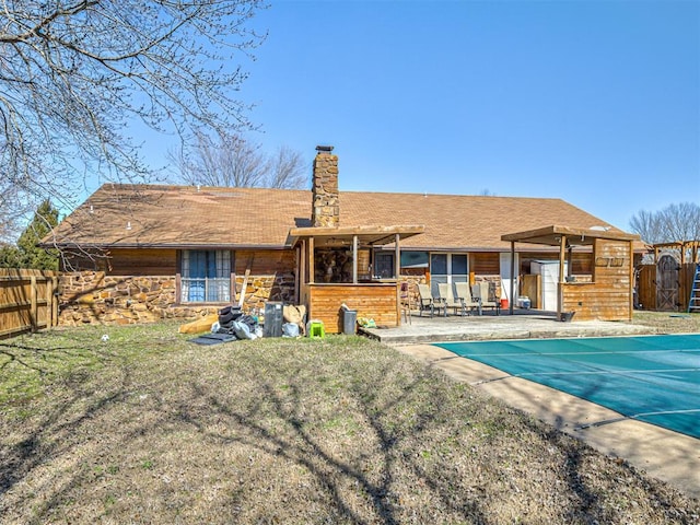 back of property featuring a fenced in pool, a patio, a chimney, and fence