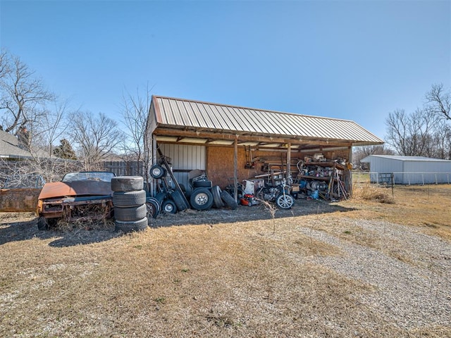 view of pole building featuring driveway and fence