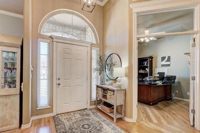 entrance foyer featuring wood finished floors, baseboards, and ornamental molding