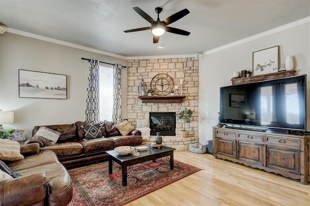 living area featuring a fireplace, a ceiling fan, crown molding, and light wood-style floors