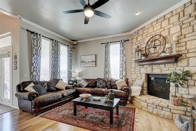 living area with wood finished floors, a ceiling fan, ornamental molding, and a fireplace