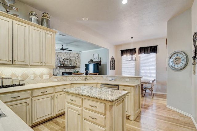 kitchen featuring decorative backsplash, a peninsula, cream cabinets, and light wood-type flooring