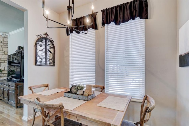 dining space with wood finished floors, a chandelier, and ornamental molding