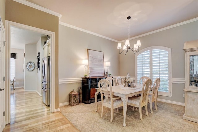 dining area with light wood-style flooring, ornamental molding, baseboards, and a chandelier