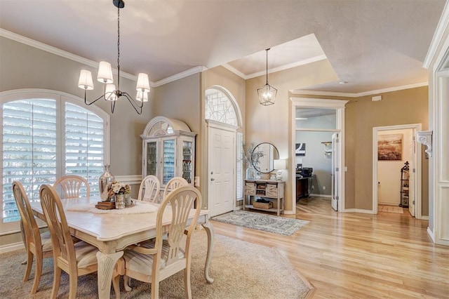 dining room featuring a notable chandelier, baseboards, crown molding, and light wood-style floors