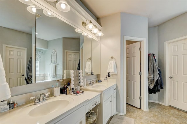 full bath with double vanity, baseboards, a closet, and a sink