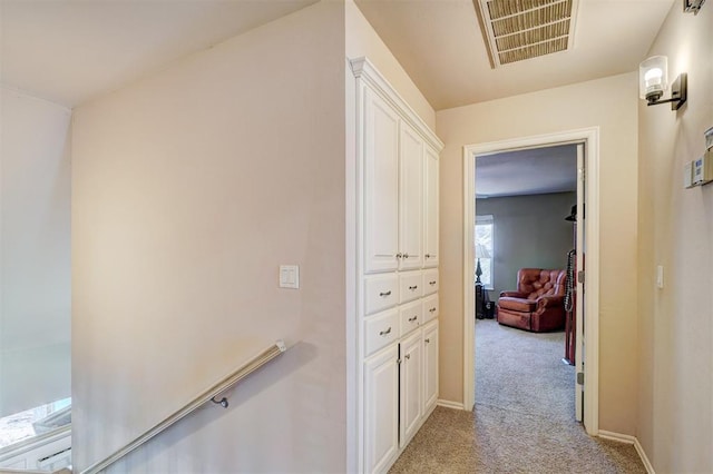 corridor featuring visible vents, light colored carpet, and baseboards