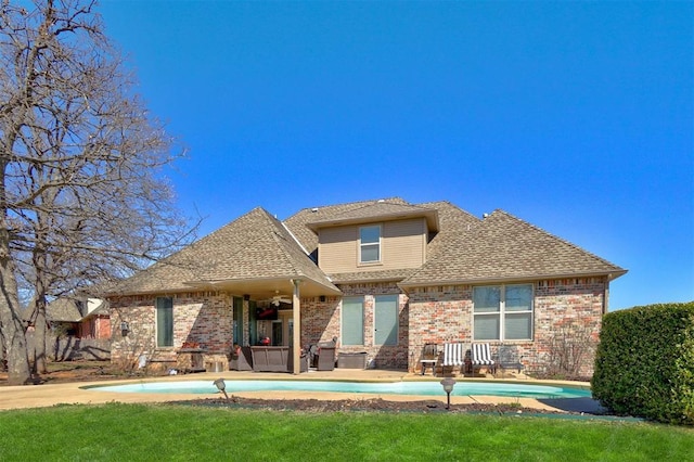 back of house featuring brick siding, an outdoor pool, and roof with shingles