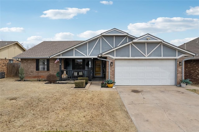 tudor home featuring a porch, concrete driveway, an attached garage, a shingled roof, and brick siding