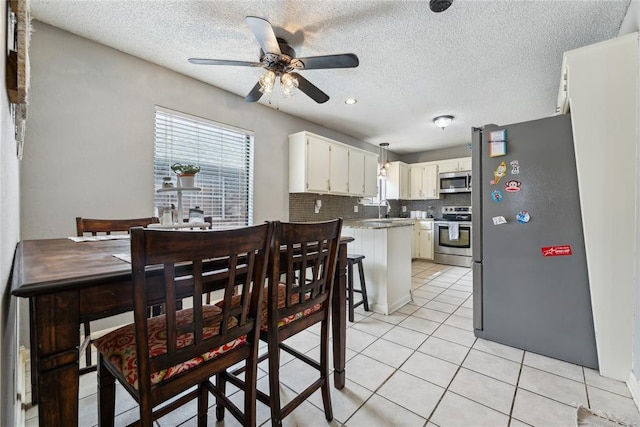 dining room with light tile patterned flooring, a ceiling fan, and a textured ceiling