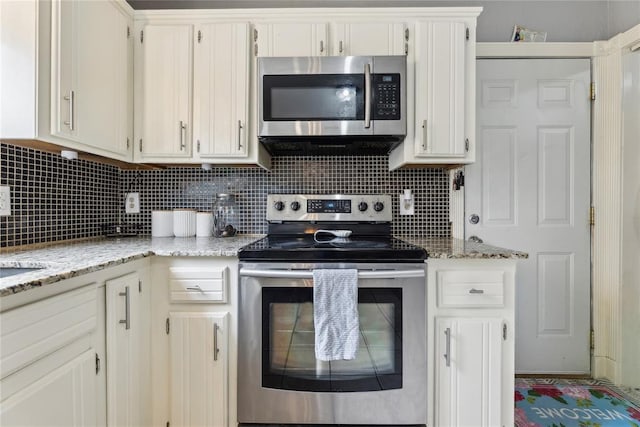 kitchen featuring decorative backsplash, light stone countertops, white cabinetry, and appliances with stainless steel finishes