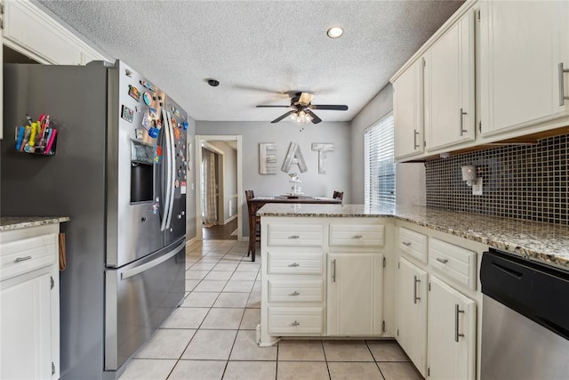 kitchen featuring decorative backsplash, appliances with stainless steel finishes, a peninsula, light tile patterned flooring, and a ceiling fan