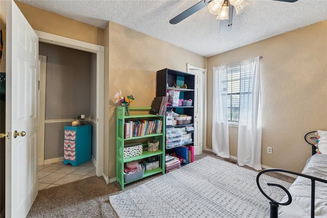 tiled bedroom featuring a ceiling fan, baseboards, a textured wall, and a textured ceiling