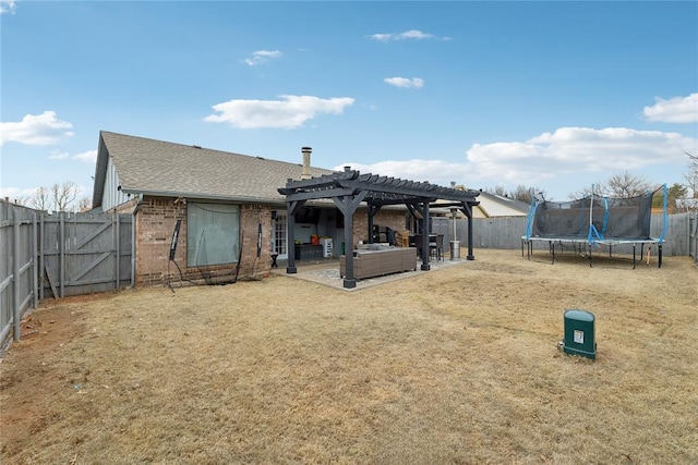 rear view of house with brick siding, a trampoline, a fenced backyard, a pergola, and a patio