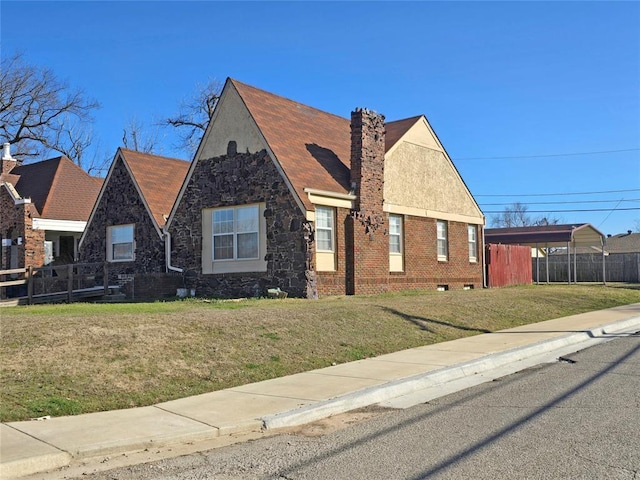 view of front of property featuring a chimney, fence, a front lawn, and brick siding