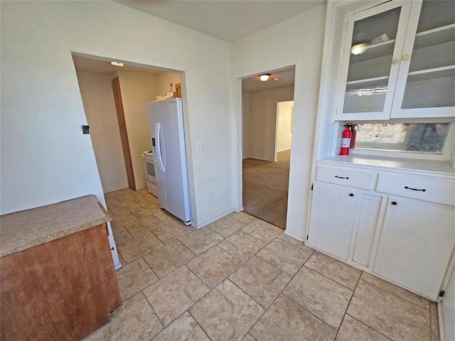 kitchen featuring white appliances, glass insert cabinets, white cabinets, and light countertops