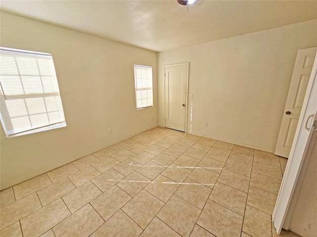unfurnished room with light tile patterned floors and a textured ceiling