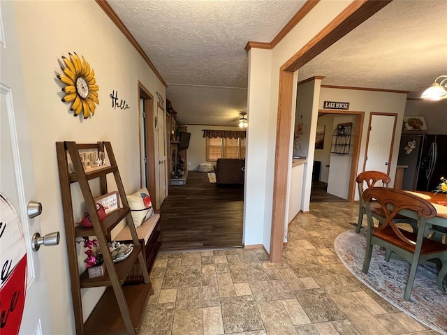 corridor featuring baseboards, a textured ceiling, crown molding, and stone finish floor