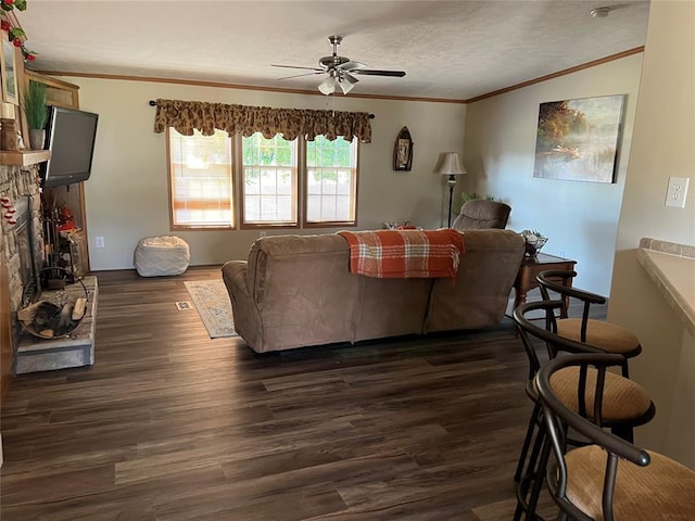 living room with ceiling fan, a textured ceiling, dark wood-style floors, and ornamental molding