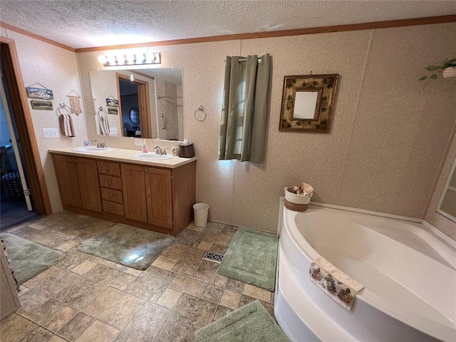 bathroom with a textured ceiling, crown molding, a bath, and a sink