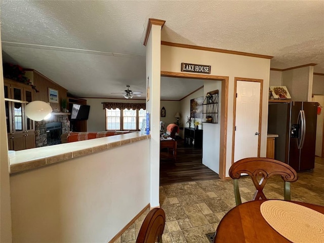 13132 Bluebird Ln, Kingston, OK 73439 - kitchen with crown molding, ceiling fan, stainless steel fridge with ice dispenser, tile countertops, and a textured ceiling
