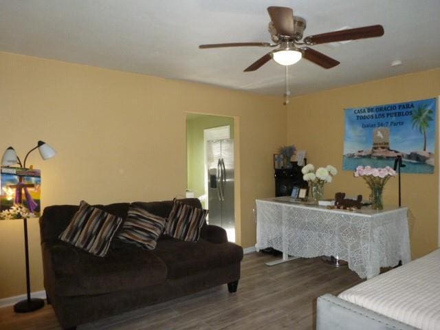 living room with a ceiling fan, baseboards, and wood finished floors