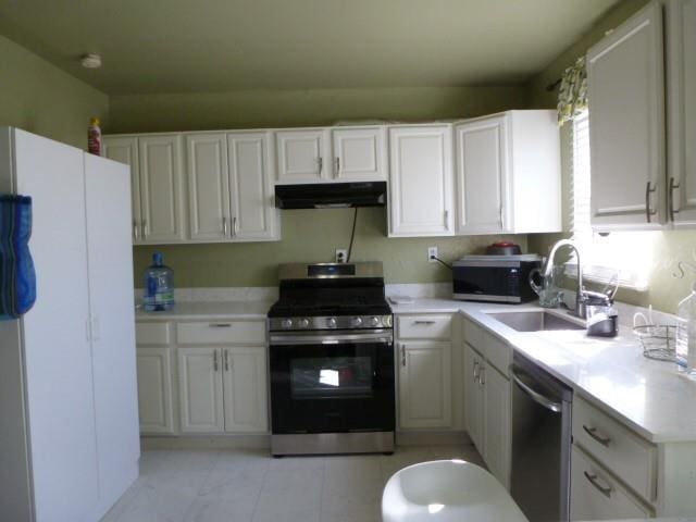 kitchen featuring stainless steel appliances, light countertops, white cabinets, a sink, and under cabinet range hood