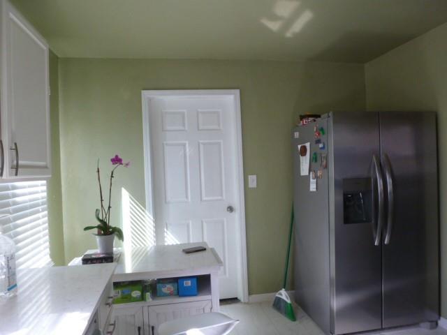 kitchen featuring light countertops, white cabinets, stainless steel fridge, and a peninsula