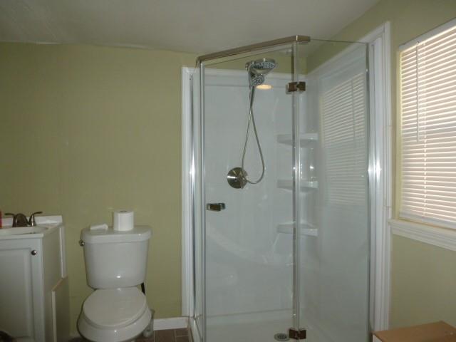 bathroom with a stall shower, a sink, toilet, and baseboards