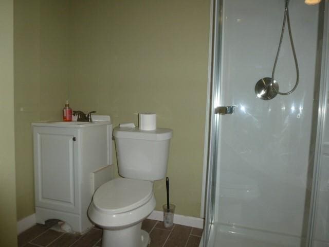 full bath featuring toilet, a shower stall, and baseboards