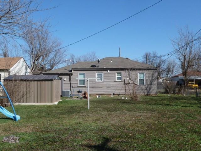 back of house with a playground, a yard, central air condition unit, a storage shed, and an outdoor structure