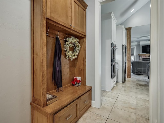 mudroom with light tile patterned floors, decorative columns, and lofted ceiling