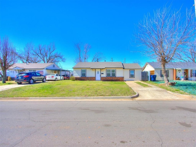 ranch-style home with brick siding, driveway, and a front yard