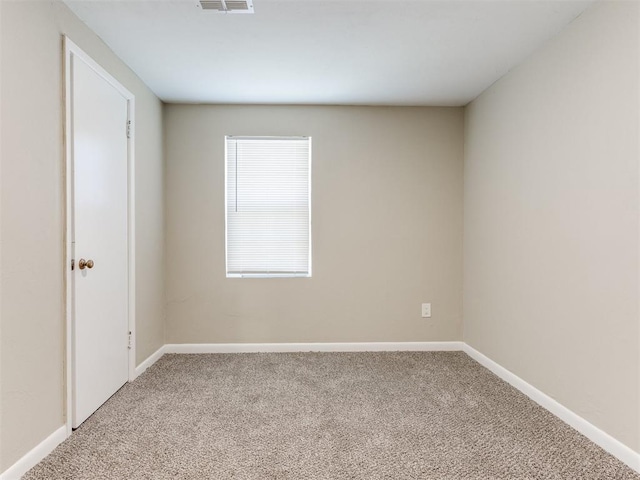 carpeted spare room with visible vents and baseboards