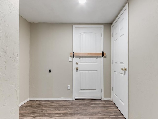 interior space with baseboards, wood finished floors, and a textured wall