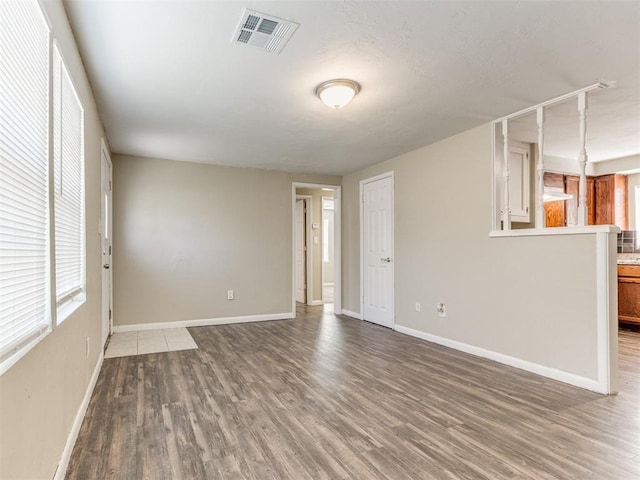 unfurnished living room featuring visible vents, baseboards, and wood finished floors