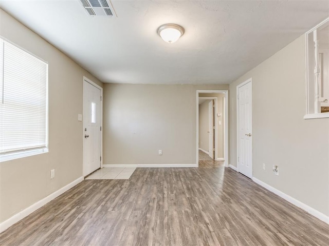 unfurnished room featuring light wood finished floors, visible vents, and baseboards